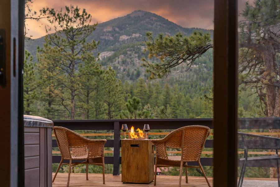 Balcony with a fire table facing a pine-covered peak at sunset