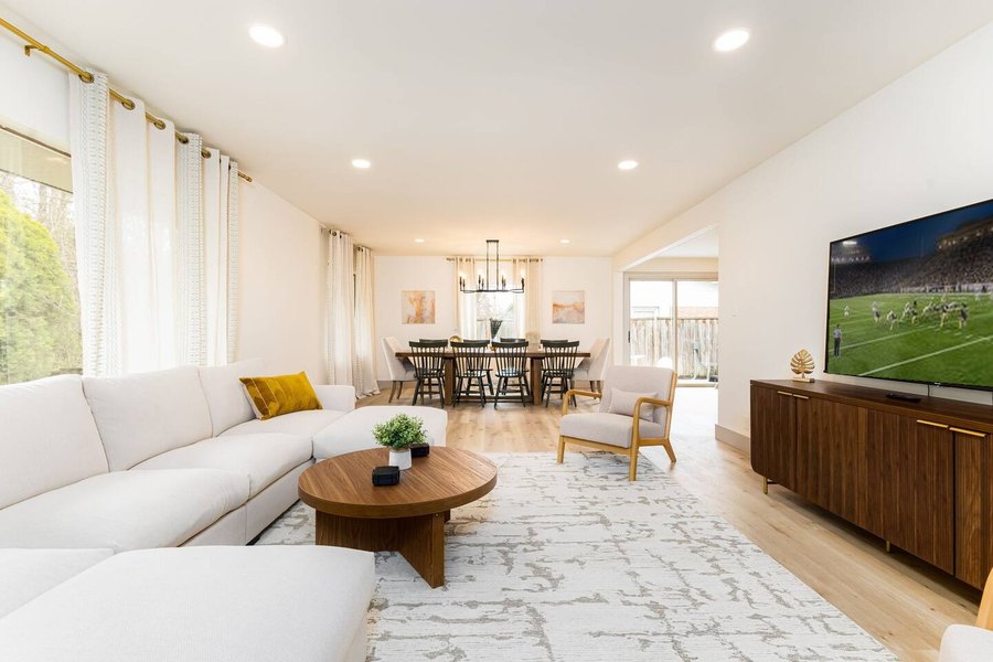 Heisman Hall living room with a white sectional and a football game on the TV