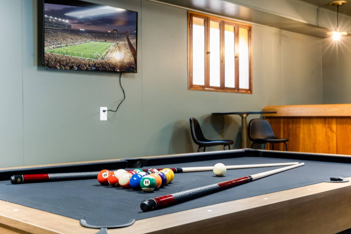 Pool table racked and ready, with a TV on the wall