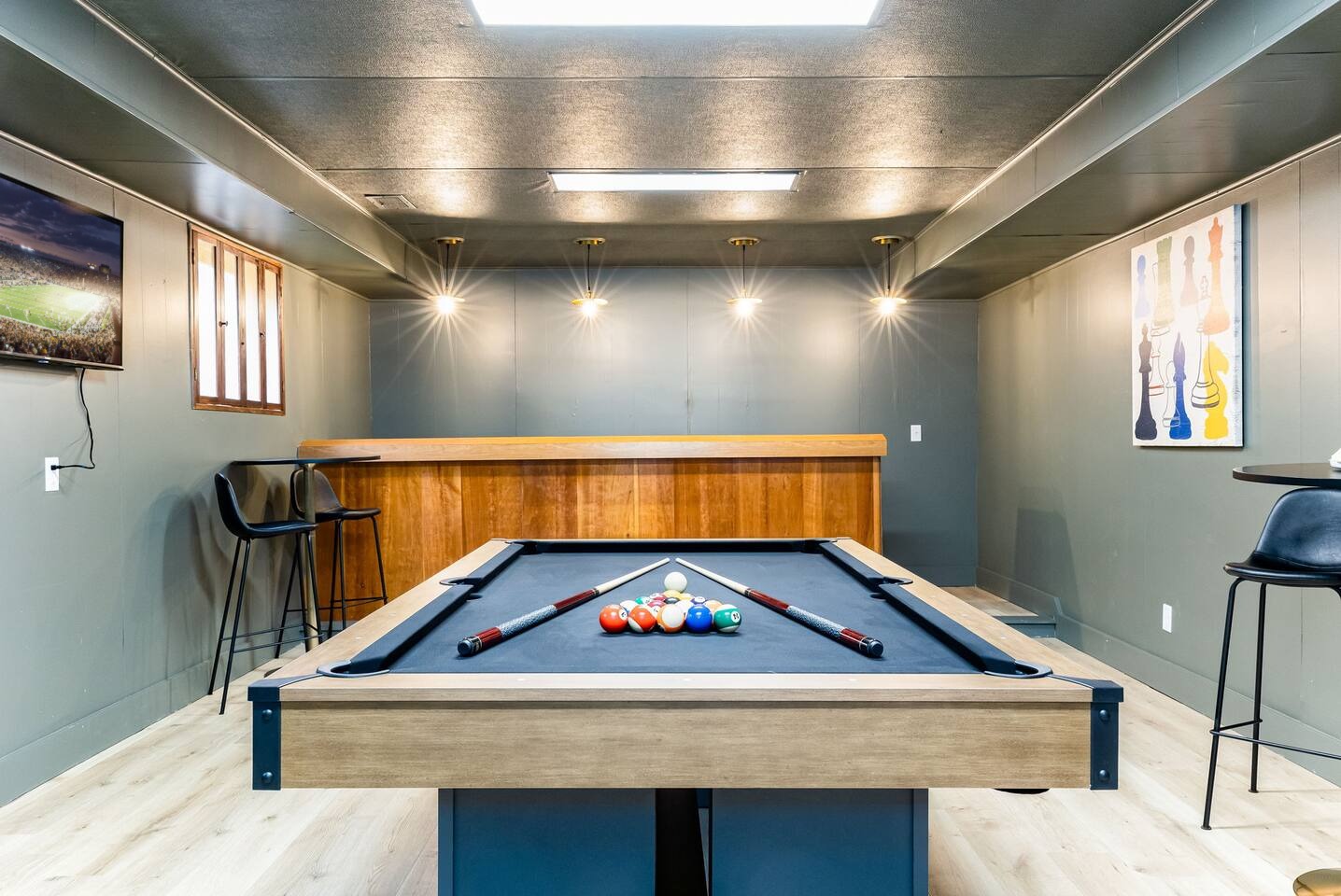 Lower-level rec room with a pool table, a wood bar and bar stools