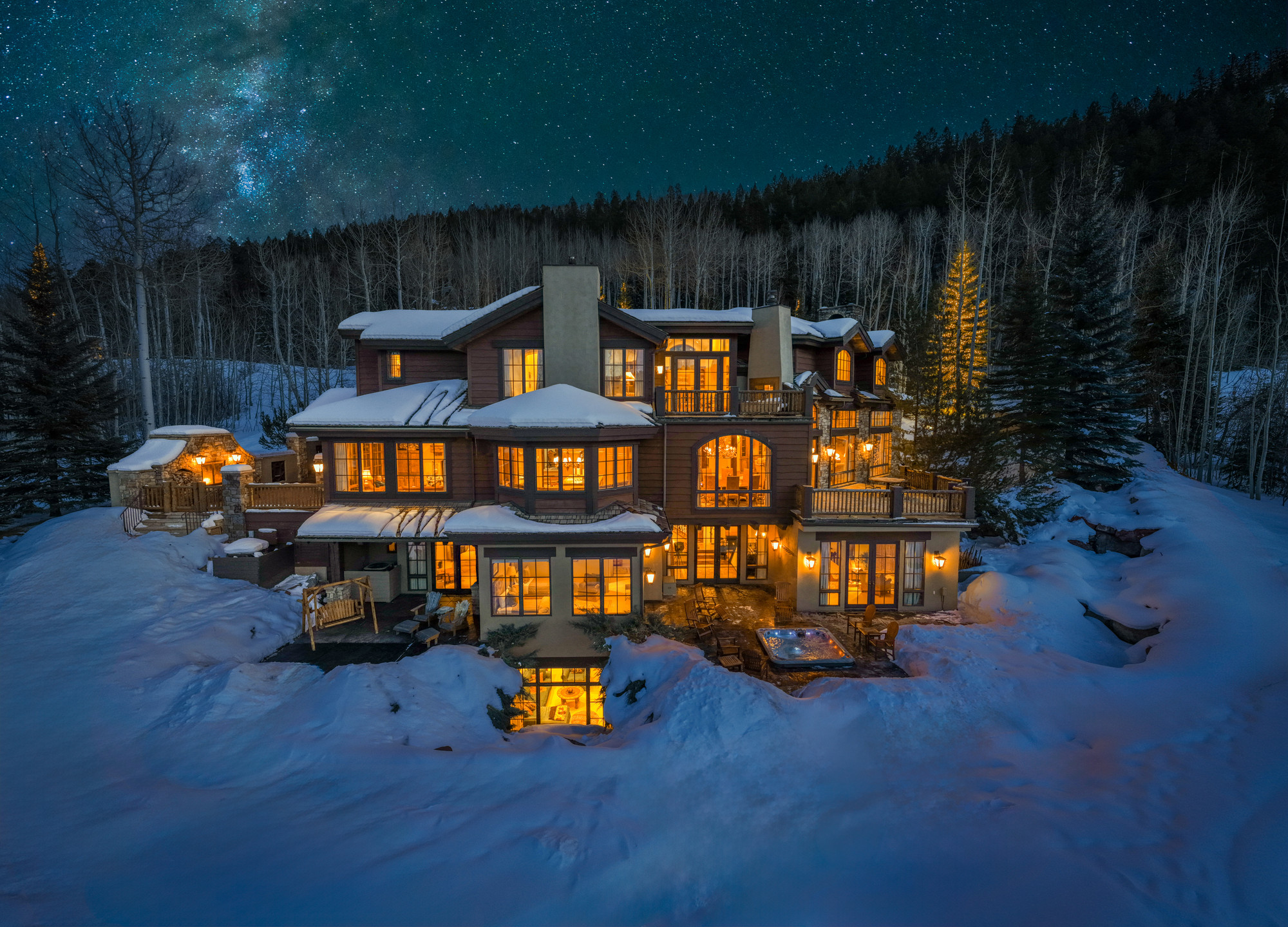 The Lodge at Aspen Highlands glowing on a snowy winter night under a starry sky