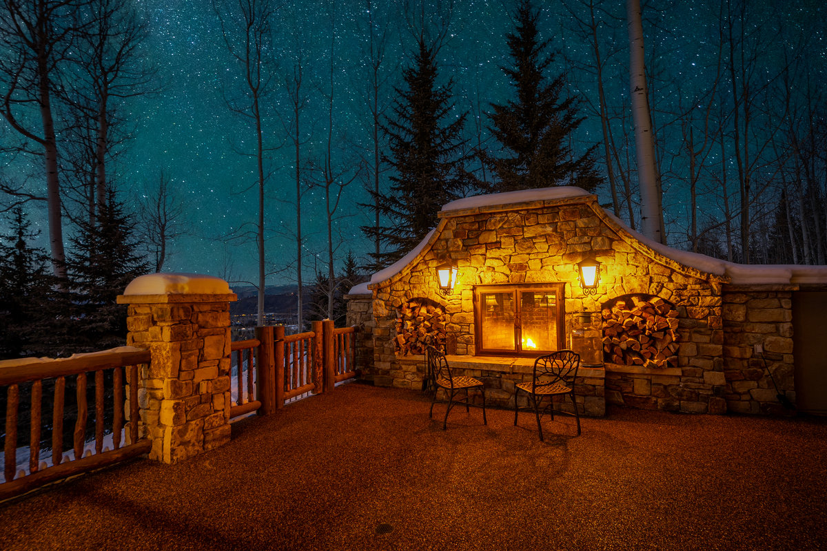 Starlit stone-fireplace patio at The Lodge at Aspen Highlands
