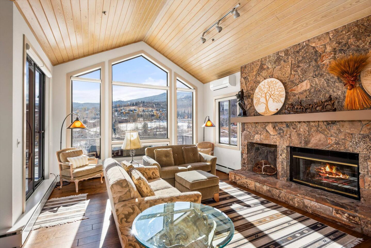 Vaulted living room with a gas fireplace and windows facing the Snowmass ski area at Snowball House